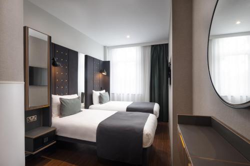 a hotel room with two beds and a mirror at Point A Hotel London Kings Cross – St Pancras in London