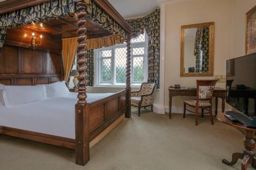 een slaapkamer met een hemelbed en een bureau bij Crewe Hall Hotel & Spa - Cheshire in Crewe
