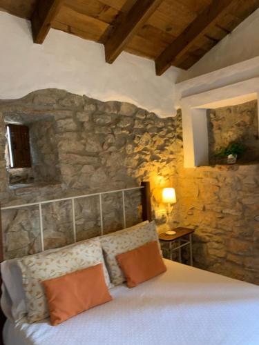 a bedroom with a bed with a stone wall at Casas de Almajar in Prado del Rey