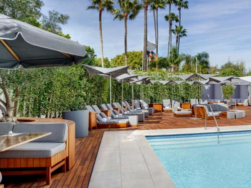 una piscina con sedie a sdraio e ombrelloni accanto a una piscina di Cameo Beverly Hills a Los Angeles