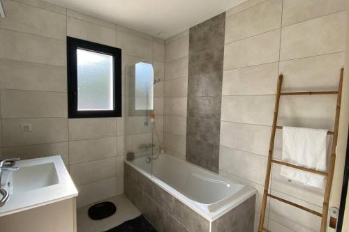 Baño blanco con bañera y lavamanos en Villa des églantines maison jacuzzi bord de mer en Saint-Jean-de-Monts