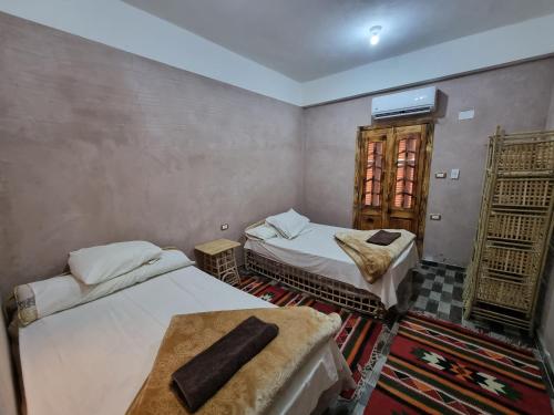 a room with two beds and a tv on the wall at quiet home in Siwa