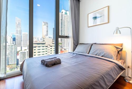 a bedroom with a large bed with a large window at Hyde Sukhumvit 11 Branded Suites in Bangkok