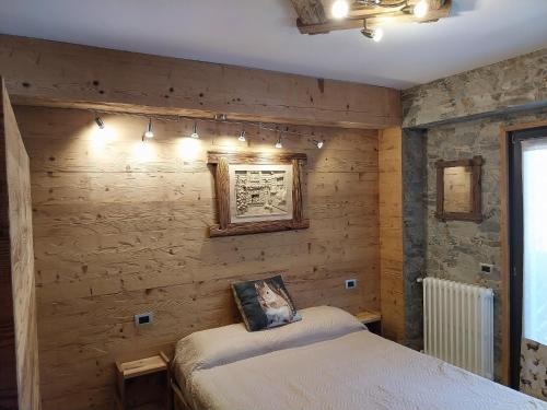 1 dormitorio con 1 cama en una pared de madera en Bertuzzi Luxury Chalet, en Aprica