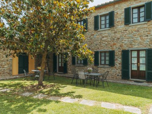 a building with a table and chairs and a tree at Rustic Farmhouse in Cortona with Swimming Pool in Cortona