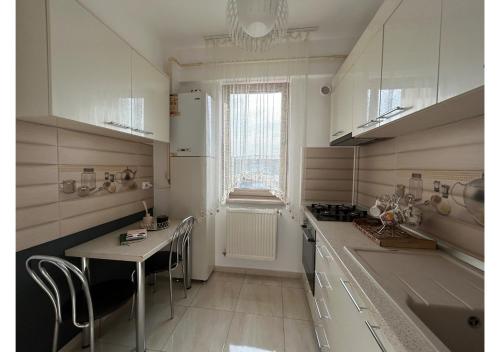een keuken met witte kasten en een tafel en een raam bij Luxury ap 2 rooms - AB House in Lunca Cetăţuii