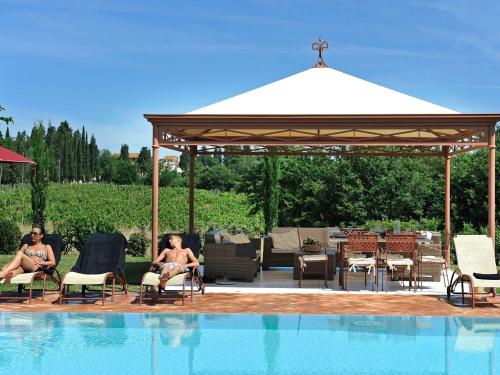 two people sitting in chairs next to a swimming pool at Pleasant villa in Peccioli with private swimming pool in Montelopio