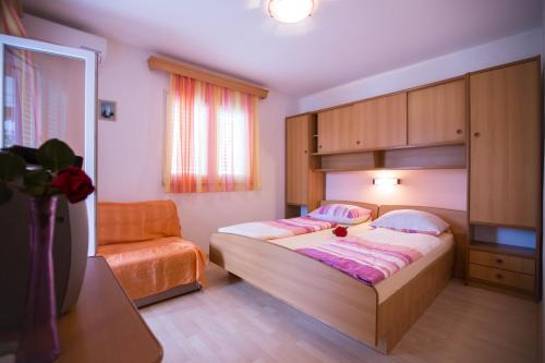 a small bedroom with a bed and a chair at Apartments Dunja Piric in Lopar
