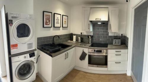 a kitchen with a washing machine and a washer and dryer at The Woden Boutique Hotel Walsall M6 J9 in Walsall