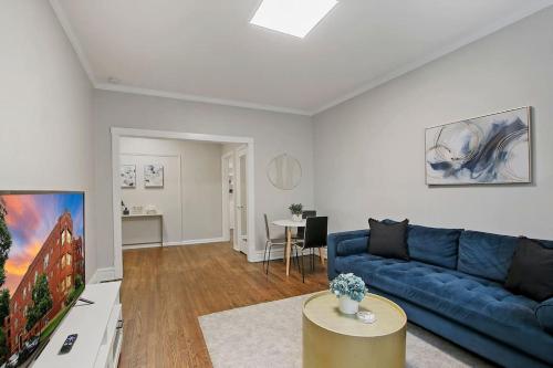a living room with a blue couch and a tv at Chic & Fully Furnished 2BR Apartment - Roscoe 1 in Chicago