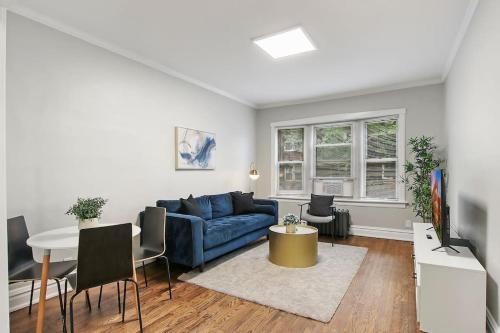 a living room with a blue couch and a table at Chic & Fully Furnished 2BR Apartment - Roscoe 1 in Chicago
