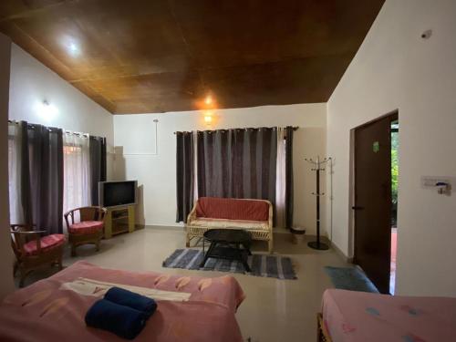 a living room with two beds and a television at Coorg Northbreeze Estate stay in Madikeri