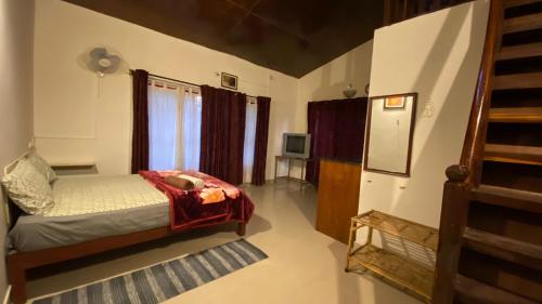 ein Schlafzimmer mit einem Bett und einem TV in einem Zimmer in der Unterkunft Coorg Sai Estate Ecobreeze Homestay in Madikeri