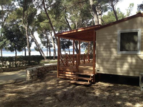 a small cabin with a wooden porch next to trees at Comfortable chalet with two bathrooms at 31 km from Zadar in Biograd na Moru