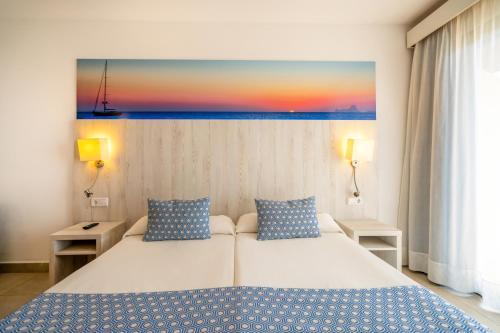 a bedroom with a bed and a painting on the wall at Club Can Bossa in Playa d'en Bossa