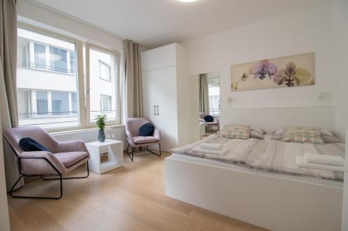 - une chambre blanche avec un grand lit et deux chaises dans l'établissement Krakovska CR Apartments, à Prague