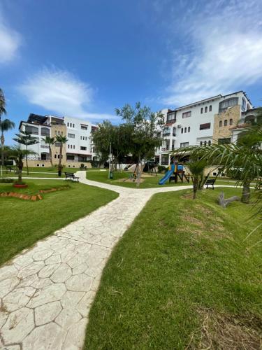 un passaggio pedonale in un parco con edifici e parco giochi di Résidence avec piscine près de la plage Martil a Martil