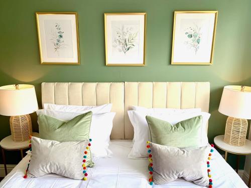 - un lit avec des oreillers blancs et 2 photos sur le mur dans l'établissement Bright modern flat in central Twickenham, à Twickenham