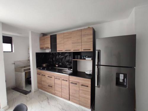 eine Küche mit Holzschränken und einem Kühlschrank aus Edelstahl in der Unterkunft Hermoso e iluminado apartamento. in Itagüí