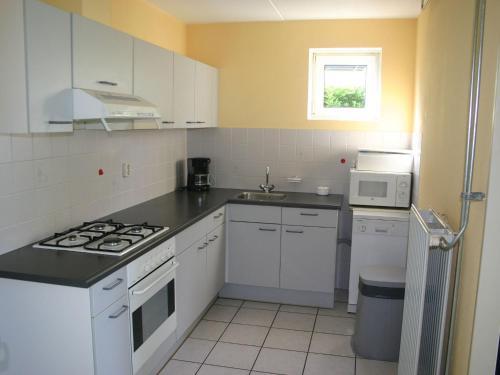 a kitchen with white cabinets and a stove top oven at Detached bungalow with dishwasher at the water in Medemblik