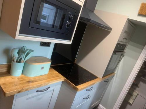 uma cozinha com um micro-ondas e um fogão forno superior em Quaint 1 bedroom cottage in Pudsey, Leeds em Pudsey