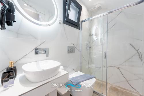 a white bathroom with a sink and a shower at Grand Wave Luxury Suites in Flogita