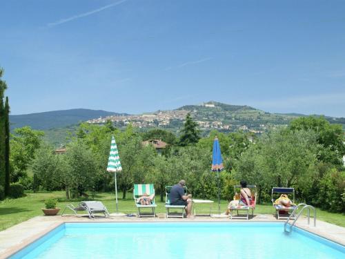 コルトーナにあるBeautiful holiday home with view over Cortona in beautiful surroundingsのプールの近くの芝生の椅子に座る人々