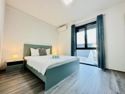 1 dormitorio con cama y ventana grande en Bleu Apartment Baile Felix, en Băile Felix
