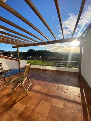 a patio with a table and chairs on a roof at Casa Rural Albores Grande Nigrán in Nigrán