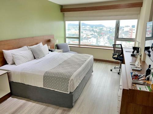 a bedroom with a bed and a desk and a window at Wyndham Garden Guayaquil in Guayaquil