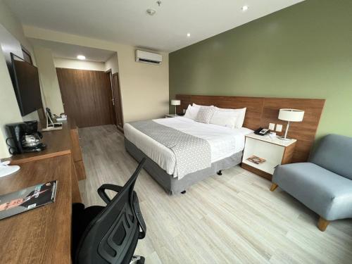 a hotel room with a bed and a chair at Wyndham Garden Guayaquil in Guayaquil