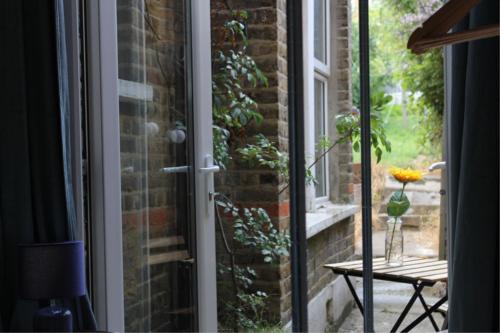 una porta a vetri con un vaso di fiori su un tavolo di Urban Retreat a Londra
