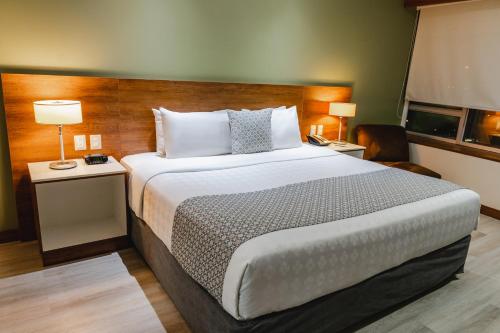 a hotel room with a large bed and two lamps at Wyndham Garden Guayaquil in Guayaquil