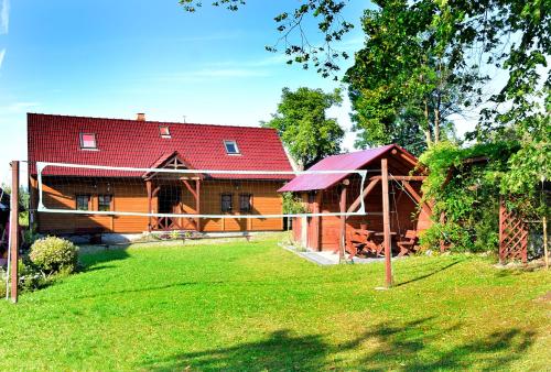 een huis met een rood dak en een groene tuin bij Chata pod Mogielicą in Zalesie