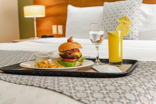 a tray with a hamburger and french fries and a glass of wine at Wyndham Garden Guayaquil in Guayaquil