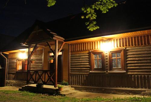een houten huis met 's nachts lichten aan de voorkant bij Chata pod Mogielicą in Zalesie