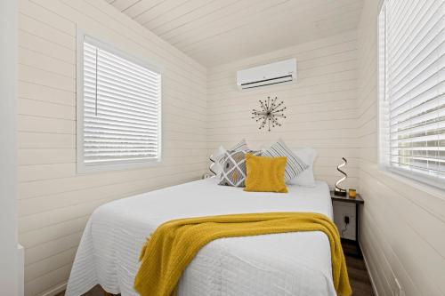 a white bedroom with a bed with a yellow blanket on it at New The Yellow Beacon-Luxury Shipping Container in Fredericksburg
