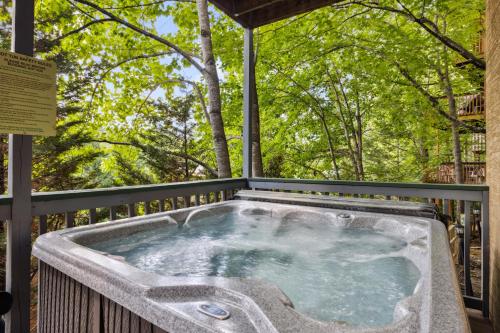 a hot tub on a deck with trees in the background at Valley Heights home in Pigeon Forge