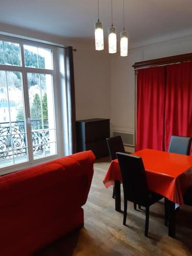 Cette chambre comprend une table et des chaises rouges ainsi qu'une fenêtre. dans l'établissement le sarciron 82, à Le Mont-Dore