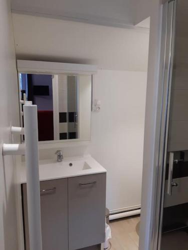 une salle de bain blanche avec un lavabo et un miroir dans l'établissement le sarciron 82, à Le Mont-Dore