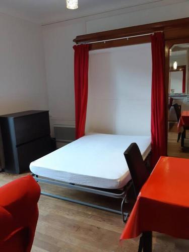 une chambre avec un lit et une table rouge dans l'établissement le sarciron 82, à Le Mont-Dore