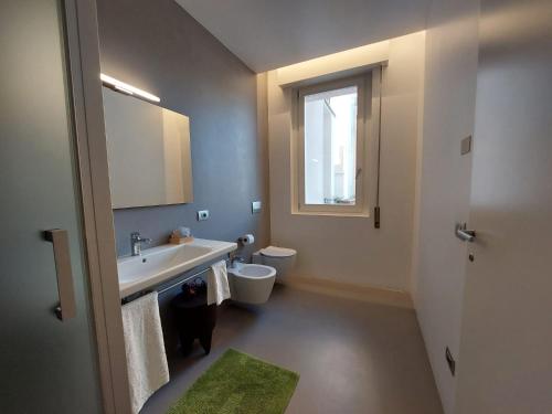 a bathroom with a sink and a toilet and a window at Casa del Corso in Pordenone
