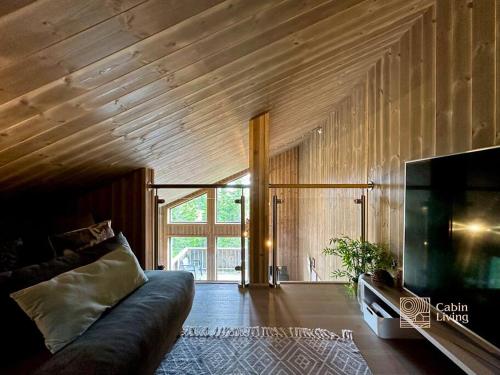 a living room with a couch and a flat screen tv at Sjusjøen ski in out, ski storage, Wifi, grill & fireplace, modern apartment! in Sjusjøen