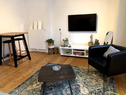 salon z kanapą, telewizorem i stołem w obiekcie Cosy renovated 1 bedroom apartment. w Antwerpii