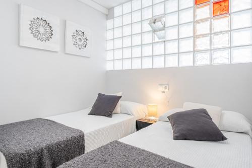 2 Betten in einem Zimmer mit weißen Wänden und Fenstern in der Unterkunft Agua Mundo 7-2 Apartment Levante Beach in Benidorm