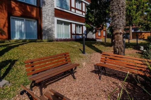 dois bancos de madeira sentados em frente a um edifício em Apartamento Novo e Completo no Centro de Gramado! em Gramado