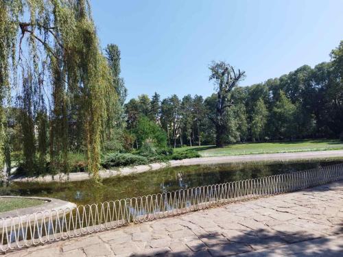 a fence next to a pond in a park at EVA Apartment in Novi Sad