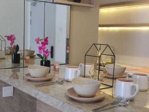 a table with bowls and plates on a counter with flowers at Mocha Suite @ The Horizon Ipoh [4 to 6 pax] in Ipoh