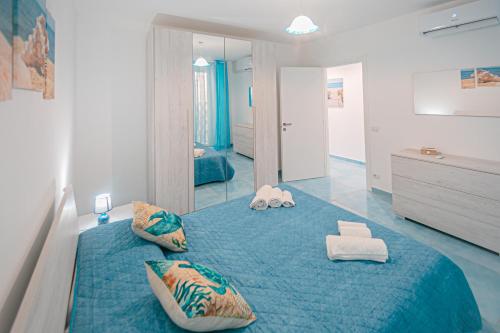 a bedroom with a large blue bed with towels on it at Scinniamare in Cefalù
