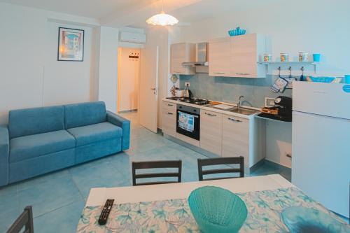a living room with a blue couch and a kitchen at Scinniamare in Cefalù